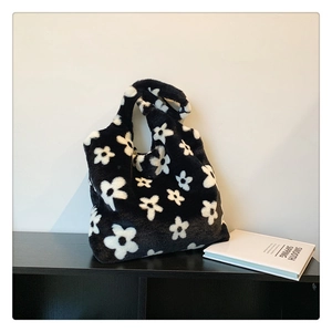 Close-up of black and white floral plush tote bag on a modern display shelf