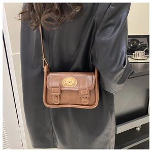Vue détaillée d'un petit sac bandoulière marron avec doubles boucles et broderie de chien