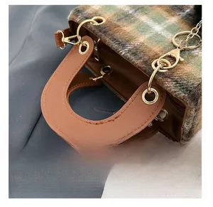 Detail presentation of plaid fabric texture and premium golden metal hardware on handbag