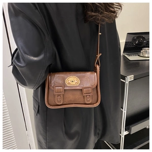 Détail d'un sac à bandoulière marron rétro avec un écusson de chiot jaune mignon