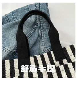 Détail des poignées renforcées en tissu noir sur un cabas en toile rayée élégant