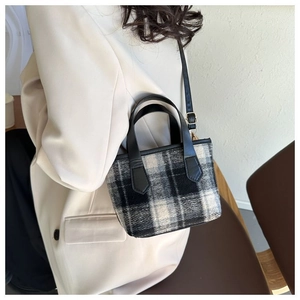 Dettaglio di una piccola borsa tote a quadri indossata a spalla da una modella in beige