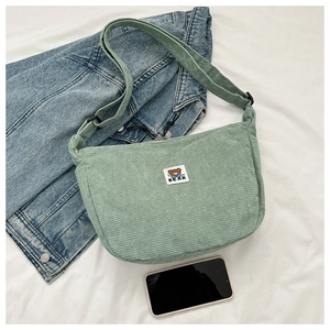 Detail of light green corduroy crossbody bag with adjustable strap and bear patch