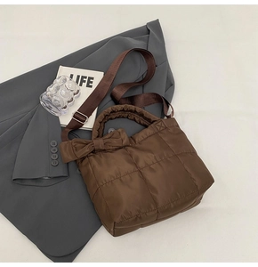 Détail d'un sac en nylon matelassé marron avec grand nœud et bandoulière réglable