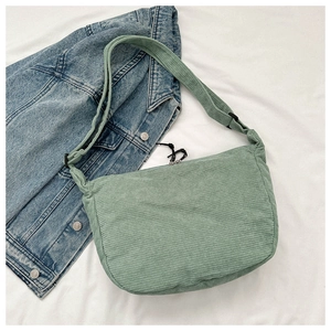 Detail of light green corduroy dumpling bag with zipper and adjustable strap