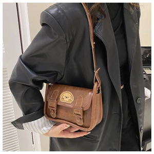 Détail du sac bandoulière vintage en cuir marron avec écusson chien cartoon et lanières
