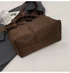 Détail du sac à main en nylon matelassé marron avec nœud latéral et bandoulière large