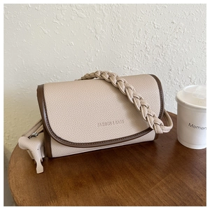 Detail of beige lychee leather crossbody bag with brown edges and woven handle