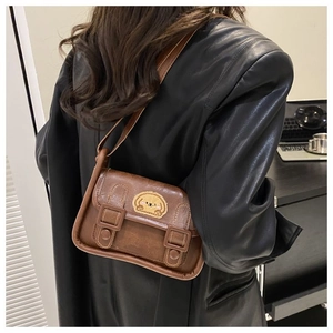 Détail du sac bandoulière marron montrant la texture similicuir rétro et l'écusson cartoon
