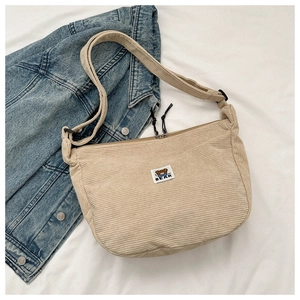 Detail of beige corduroy dumpling bag featuring a cute bear patch and adjustable strap