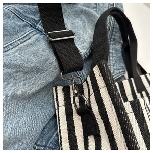 Détail d'un sac cabas en toile rayée avec bandoulière réglable et crochet en métal noir