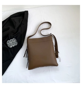 Detail view of brown vintage PU leather tote bag featuring long decorative side tassels