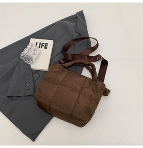 Détail d'un sac cabas marron matelassé avec bandoulière large et accessoires chic