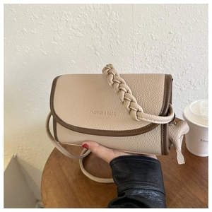 Detail of beige textured leather crossbody bag with woven handle and elephant charm