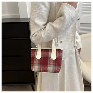 Dettaglio di una mini borsa a tracolla a quadretti indossata su un abito in tweed