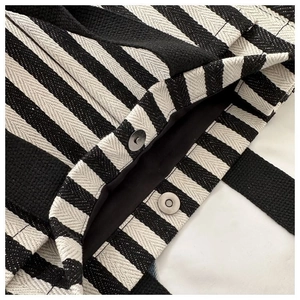 Détail du fermoir magnétique et de la doublure noire d'un sac cabas en toile rayée