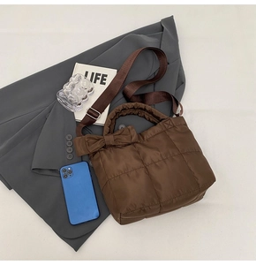 Détail de vue de dessus d'un sac à main matelassé marron avec un grand nœud décoratif
