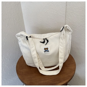 Detail of white corduroy tote bag featuring a cute bear embroidery and MF BEAR text logo