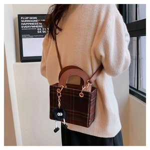 Detail of vintage brown plaid tweed bag with leather handle and cute plush ball charm