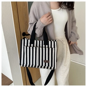Détail du sac cabas en toile rayée avec poches avant et étiquette de mode en cuir