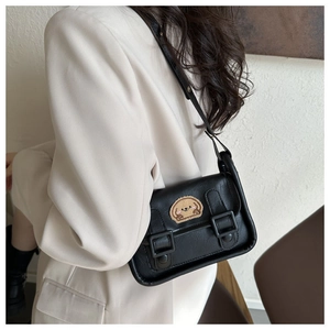 Détail d'un sac bandoulière noir avec écusson chiot et sangles de style preppy