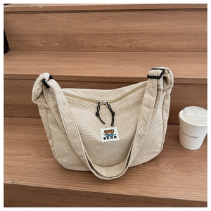 Detail of corduroy crossbody bag with MF BEAR patch and zipper on wooden steps