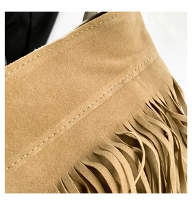 Macro shot of tan suede handbag featuring detailed stitching and long fringe accents