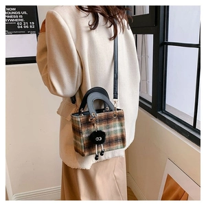 Detail of checkered tweed crossbody bag with round handle and plush pompom charm