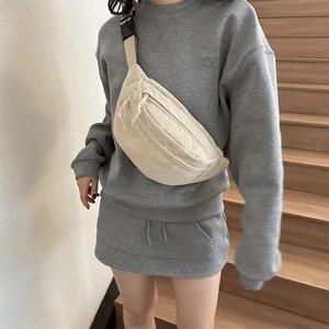 Beige corduroy crossbody chest bag with adjustable strap worn by model in casual setting
