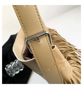 Detail of adjustable strap and silver buckle on a tan suede tote with long tassels