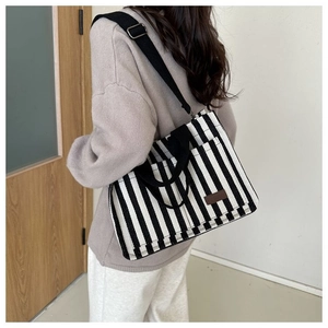 Détail du sac fourre-tout en toile rayée avec patch en cuir et large bandoulière