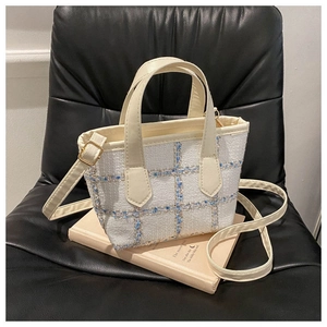 Dettaglio della borsa a tracolla in tweed con motivo a quadri blu e oro e manico in pelle