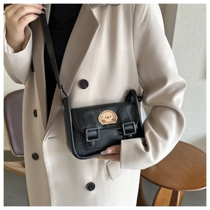 Détail du sac à bandoulière en cuir noir avec broderie mignonne de chiot beige de dessin