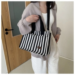 Détail du sac cabas en toile rayée avec poches extérieures et écusson en cuir marron