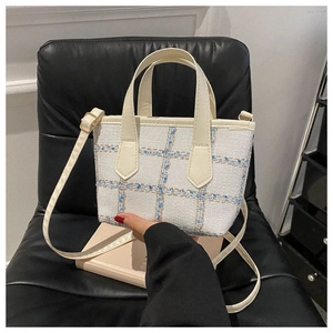 Dettaglio mini borsa tote in tweed con motivo scozzese blu oro e manici in pelle