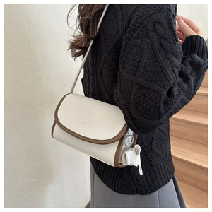 Detail of color-block flap bag in white and brown leather with elephant charm