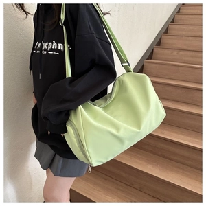 Detail view of a large green nylon crossbody bag showing the wide strap on a model