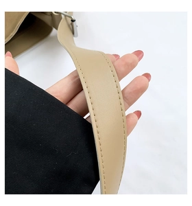 Close-up of khaki leather bag strap with fine stitching and silver metal buckle detail