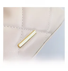 Detailed close-up of quilted beige leather bag with elegant gold metal buckle hardware