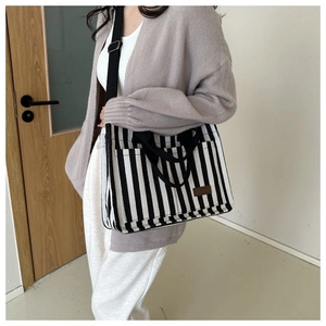 Détail du sac cabas en toile rayée avec bandoulière réglable et étiquette cuir