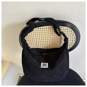 Close-up of black corduroy fabric texture and cute cartoon bear label on the crescent bag