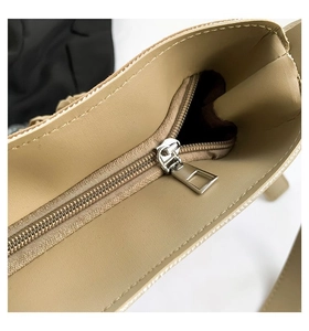 Detailed macro view of the silver metal zipper and brown fabric lining of the beige tote bag