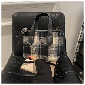 Dettaglio borsa a mano in tweed a scacchi con manico in pelle e dettagli metallici dorati