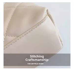 Macro shot of precise stitching and quilted leather texture on a cream bucket bag
