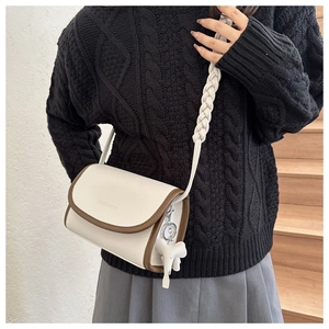 Detail of cream crossbody bag with contrast brown trim and thick woven shoulder strap