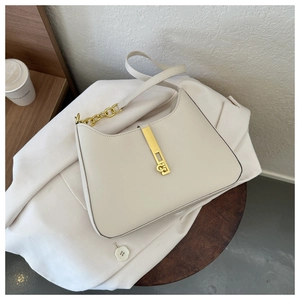 Detail of minimalist beige faux leather shoulder bag with golden metallic clasp on a blazer