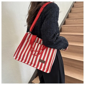 Détail du sac fourre-tout rayé rouge et blanc avec sangle et écusson en cuir