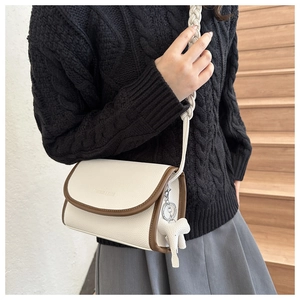 Close-up of beige lychee leather crossbody bag with brown trim and elephant charm