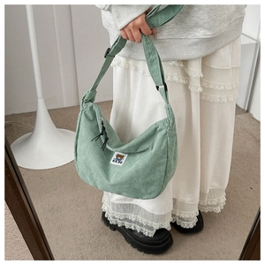Detail of sage green corduroy hobo bag with adjustable strap and cute bear patch detail
