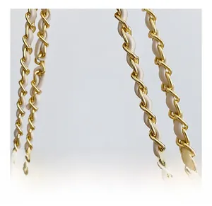 Macro shot of gold-tone metal chain intertwined with beige leather strap detail